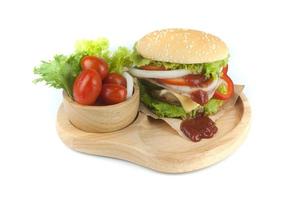 hamburguesa de cerdo casera con tocino a la parrilla que contiene verduras, queso, lechuga, cebolla, chile, especias en un plato de madera aislado en un fondo blanco foto