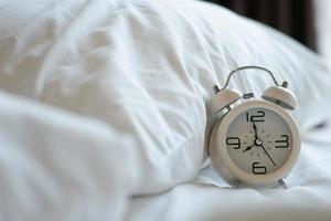 Retro white alarm clock On the white mattress in the bedroom photo
