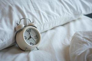 Retro white alarm clock On the white mattress in the bedroom photo