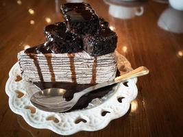 pastel de chocolate con brownie y vainilla en un plato blanco sobre una mesa de madera en una cafetería. enfoque selectivo foto