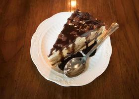 Banana Vanilla Cake with Chocolate in a white dish placed on a wooden background in a cafe.Selective focus photo