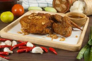 Fried chicken with spices on wooden plate with sauce and vegetables