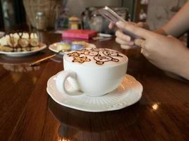 café capuchino y mujer de negocios sosteniendo un teléfono descansando en un café foto