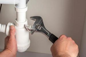 Plumber with adjustable wrench repairing pipes photo