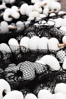 Black fishing net with white corks in Santona harbour, Cantabria, Spain. Vertical image.