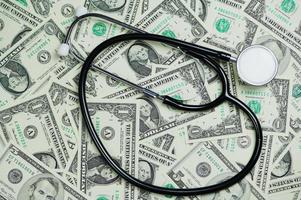 one and five Dollar banknotes as background and a stethoscope lying on the bills photo