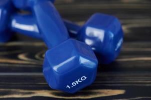 two blue dumbbells against wooden background photo