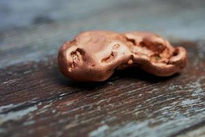 close up of a solid copper nugget against wooden background with copy space photo