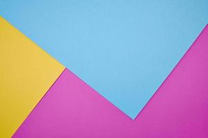 blue, magenta and yellow colored papers laid frame filling as background photo