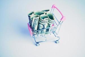 shopping cart with dollar banknotes on white background photo