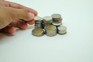 Close up hand picking or adding baht coin  isolated with white background. Saving money concept. photo