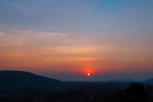 hermoso cielo al atardecer en las montañas. paisaje de campo bajo el cielo escénico al fondo del atardecer. foto