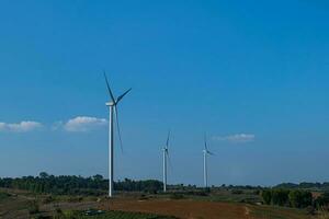 Wind turbine farm on mountain landscape with blue sky background. Wind power renewable energy concept. photo