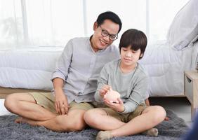 Asian father is teaching his son the saving lesson for investment in education and future planning photo