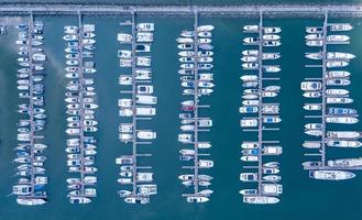 puerto marítimo para yates, lanchas motoras, servicio de estacionamiento de veleros y amarres para millonarios de lujo y ricos en vista aérea con muchos barcos anclados a lo largo de la bahía del muelle foto