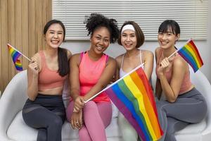 grupo de mujeres de la diversidad en ropa deportiva sosteniendo la bandera del arco iris lgbtq para el mes del orgullo para promover la igualdad y las diferencias del concepto de homosexualidad y discriminación foto