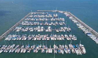 Marine port for yacht, motorboat, sailboat parking service and moorings for luxury and wealthy millionaire in aerial view with many ships anchoring along the dock bay photo