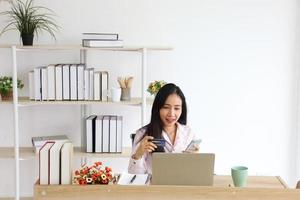 Asian woman using credit card for online banking service to purchase product from Internet with copy space photo