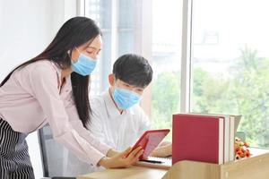 Employees working from home office while wearing medical face mask for social distancing in new normal situation for protecting and preventing the infection of corona virus or covid-19 photo