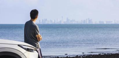 Asian man looking at the urban business skyline of financial district over the lake for future vision and inspiration concept in property and real estate investment usage photo