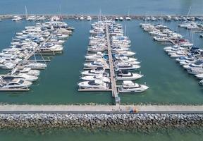 puerto marítimo para yates, lanchas motoras, servicio de estacionamiento de veleros y amarres para millonarios de lujo y ricos en vista aérea con muchos barcos anclados a lo largo de la bahía del muelle foto