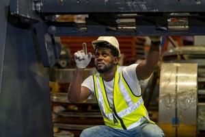 African American mechanic worker is checking the gear for hydraulic machine inside metal steel manufacturing factory for maintenance and inspection concept photo