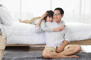 Asian father and son spending memorable time together during weekend on comfortable bedroom photo