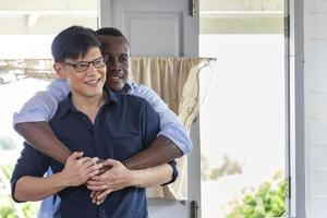 diversidad de género de la pareja gay lgbtq entre etnias asiáticas y africanas abrazándose en casa por el matrimonio entre personas del mismo sexo y el concepto del mes del orgullo