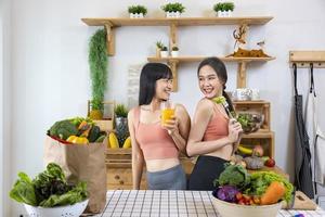 Asian sister is having a healthy food and drink while helping each other cooking in kitchen for vegan, vegetarian and plant based ingredient concept photo