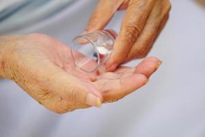The hand of an asian elderly female or senior person or an old woman hold a cup of medicine or pouring medicine on hand. Healthcare and medical concept. photo