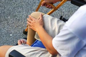 la imagen de enfoque de la mano del paciente sosteniendo una muleta, mientras se sienta en una silla de ruedas y se lesiona el tobillo. concepto médico y de salud. foto