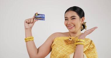 retrato de mulher tailandesa em traje tradicional, segurando o cartão de crédito. fêmea olhando para a câmera e sorrindo com fundo branco isolado. video