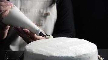 Lady making cake edge cream docoration over black background