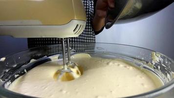 Lady is making homemade cream cake using electric portable mixer machine video