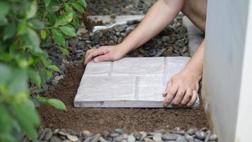 le jardinier travaille avec la décoration du sol du jardin à la maison en utilisant une dalle de béton et un matériau en pierre video