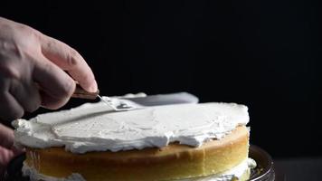 Chef lady putting cream on top of cake while making homemade bakery over black background video