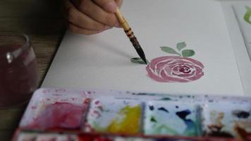 Woman paints the leaves of a rose with watercolors video