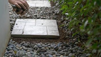 el jardinero está trabajando con la decoración del suelo del jardín doméstico utilizando losas de hormigón y material de piedra video