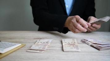 hombre contando billetes de banco dinero de baht tailandés, imágenes en cámara lenta video