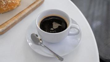 una taza de café en una mesa blanca con tiempo de descanso, concepto de comida. primer plano de un vaso de refresco de mezcla de espresso caliente con espacio de copia foto