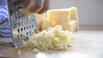 vrouw die kaas bereidt voor koken met kaasrasp in de keuken - mensen die voedsel maken met kaasconcept video