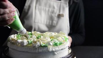 Köchin, die Rosen aus Sahne für die Dekoration von Kuchen herstellt, während sie hausgemachte Backwaren von oben auf schwarzem Hintergrund macht video