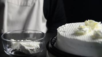 Chef lady making roses from cream for cake topping decoration while making homemade bakery over black background video