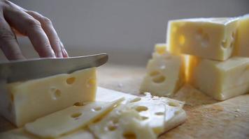 mujer cortó rebanadas de queso para cocinar usando un cuchillo en la cocina - gente haciendo comida con concepto de queso video