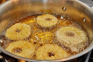 Cooking apple pancake. Apple donut in boiling oil