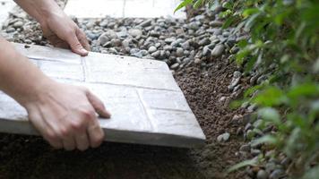 el jardinero está trabajando con la decoración del suelo del jardín doméstico utilizando losas de hormigón y material de piedra video