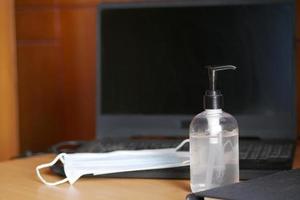 Close up of blue surgical masks and hand sanitizer on table photo