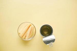 maíz para bebés en un bol con un recipiente de lata vacío sobre fondo amarillo foto