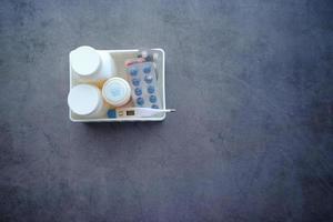 contenedor de píldoras médicas, blister y termómetro en un organizador de plástico foto