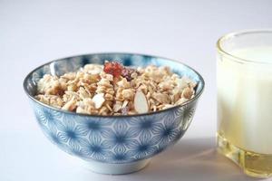 Musli casero en un bol, vaso de leche y pan en la mesa foto